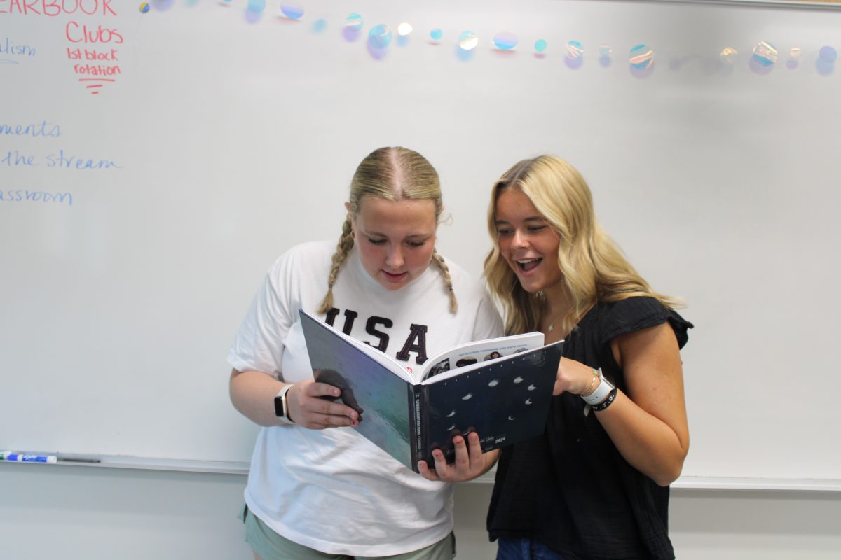 Yearbook editors Katie Bond and River McMillian looking at the previous yearbook.