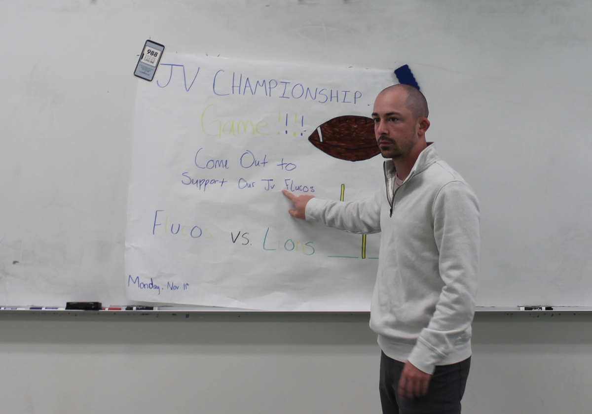 FCHS Marketing teacher Alexander Frederick pointing to a poster. Photo courtesy of Topher Huff.