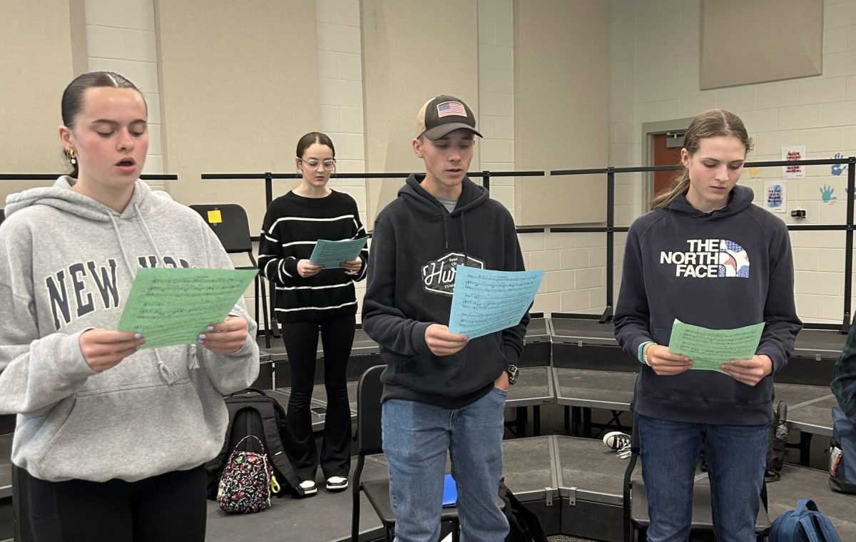 Choir students use their sheet music to rehearse for their performances.