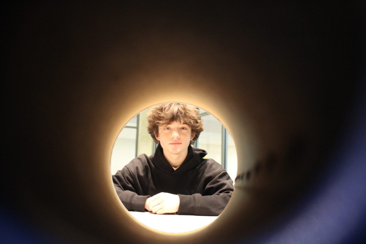 Junior Cassidy Relyea looking through a megaphone in the FCHS library.