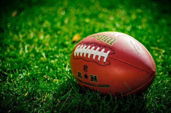 A football on grass. Photo courtesy of Elliot Chau under Creative Commons CC0 https://freerangestock.com/photos/163840/close-up-of-an-american-football-on-grass.html