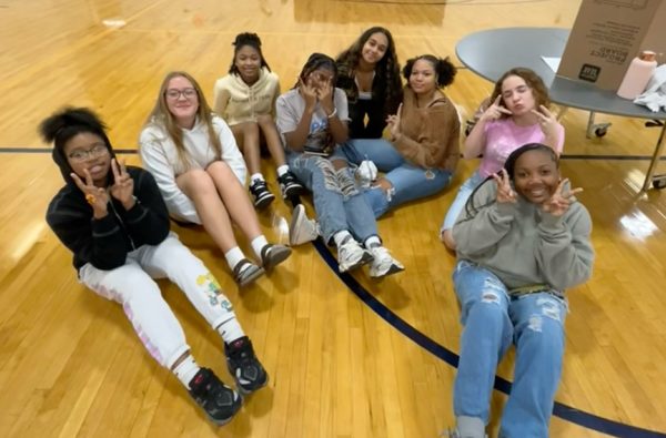 African American Heritage and Culture club members pose next to their culture fair poster.