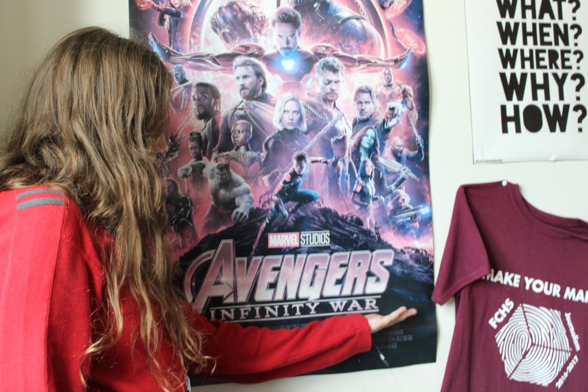 Student Sophie long in front of the "Infinty Wars" poster in Elizabeth Pellicane's classroom.  