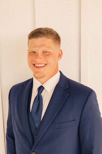 New Coach, Jacob Critzer, wearing a suit smiling at the camera. 