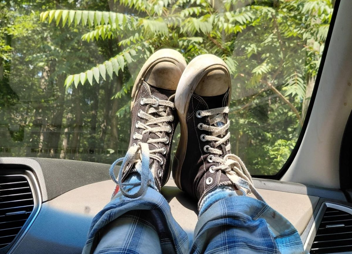 Sophomore Ziva Lewis' shoes on the dashboard of a car with trees in the background.