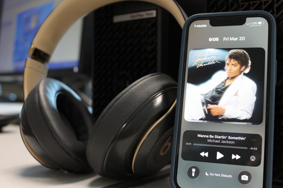 Photo taken of headphones with album cover on phone.