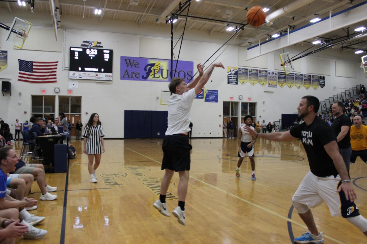 Sophomore Matt Richards takes a shot on the basket while teacher Danny Reed plays defense at the April 22 Teachers vs. Students Basketball game in the gym