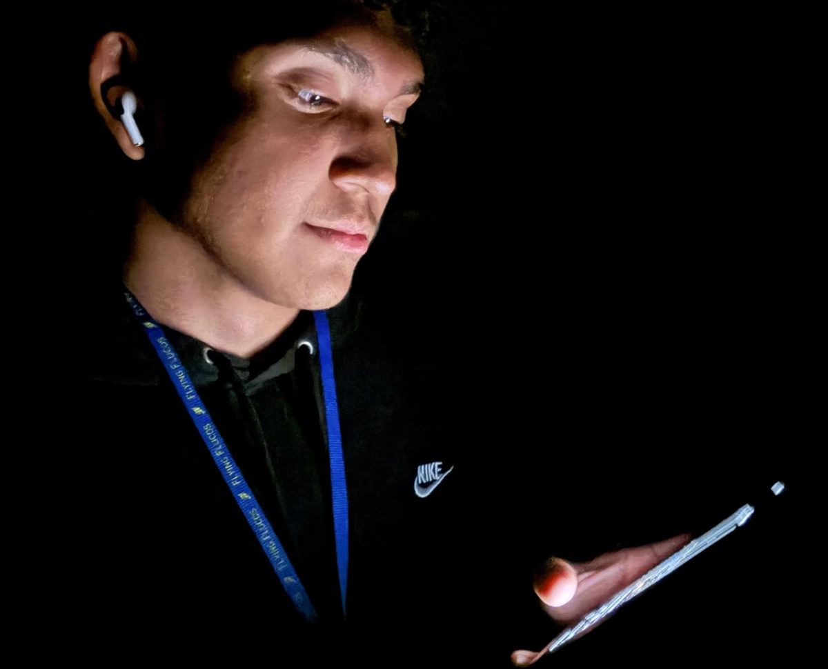 Sophomore Alan Menendez looks at his phone in the dark. 