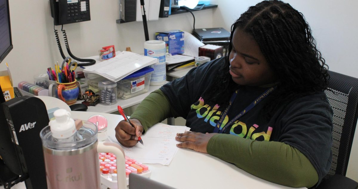 Danna Djinigou grades a work sheet from a student.