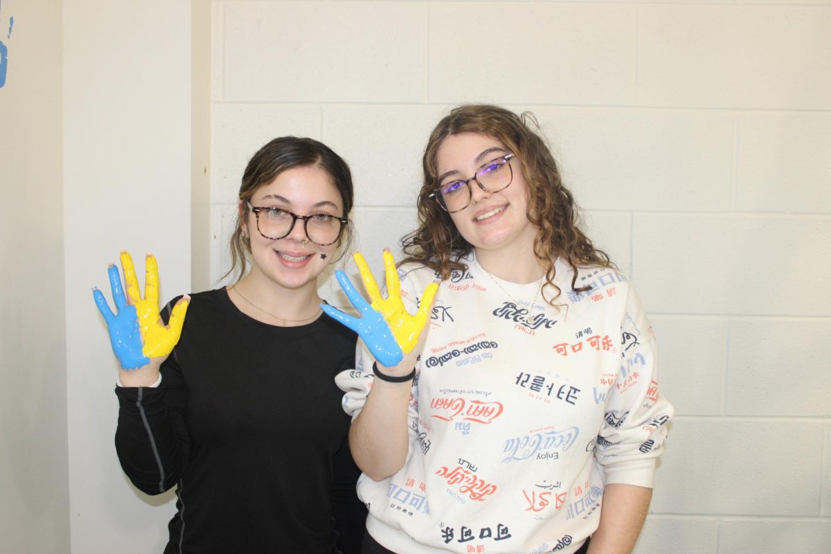 Seniors Isabella Ott and Jersie Belew prepare to place their handprints together. "We've been waiting to do this for a while and have been so excited. We've been friends since the third grade, so doing it together is special because it shows we finished strong," said Belew.