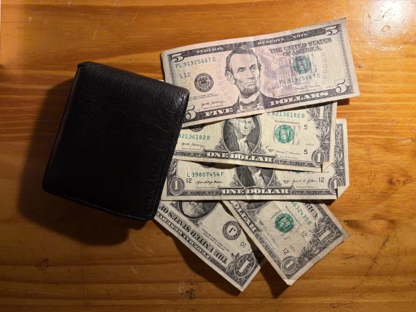 Money spread on a table with a wallet 
